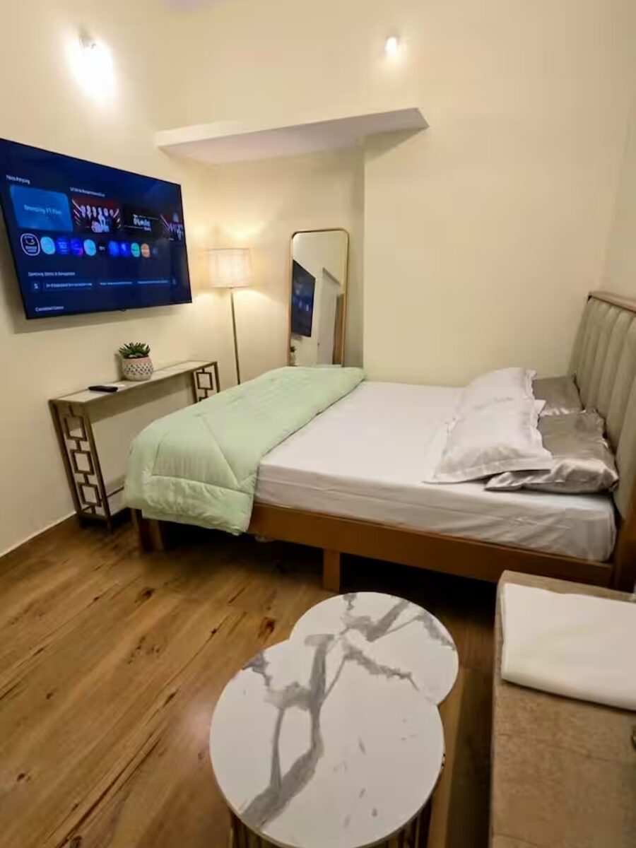 Bedroom with a comfortable bed, wall-mounted TV, and mirror