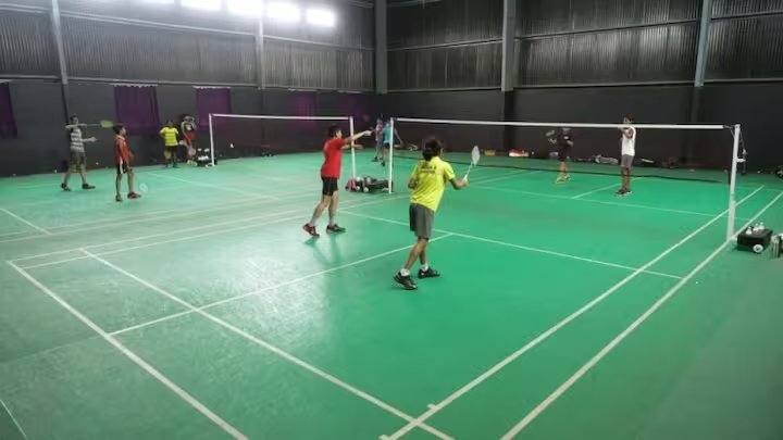 Indoor badminton courts with players mid-game